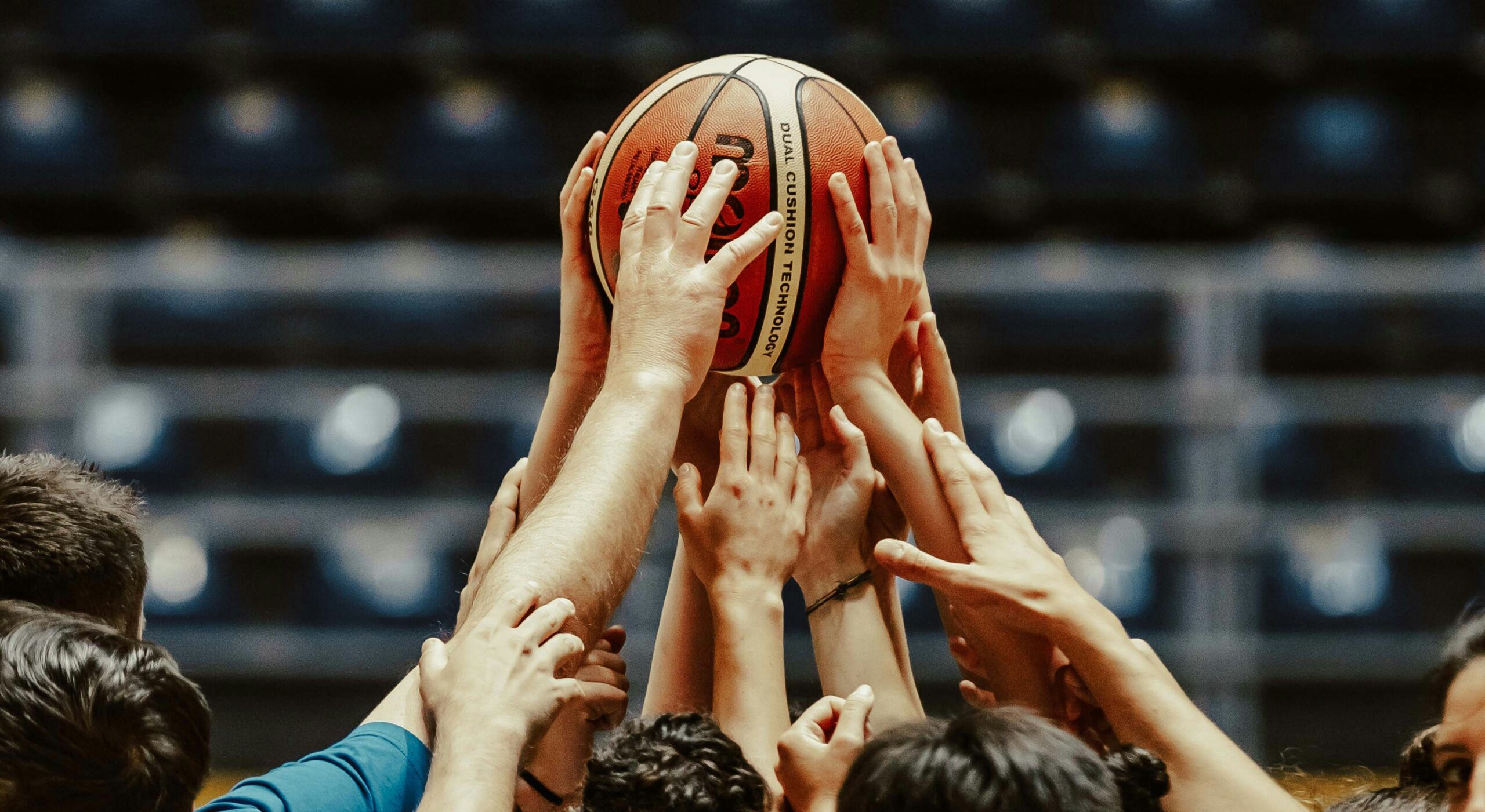 Joueurs de basketball mettant tous une main sur le ballon au milieu du rassemblement de l'équipe