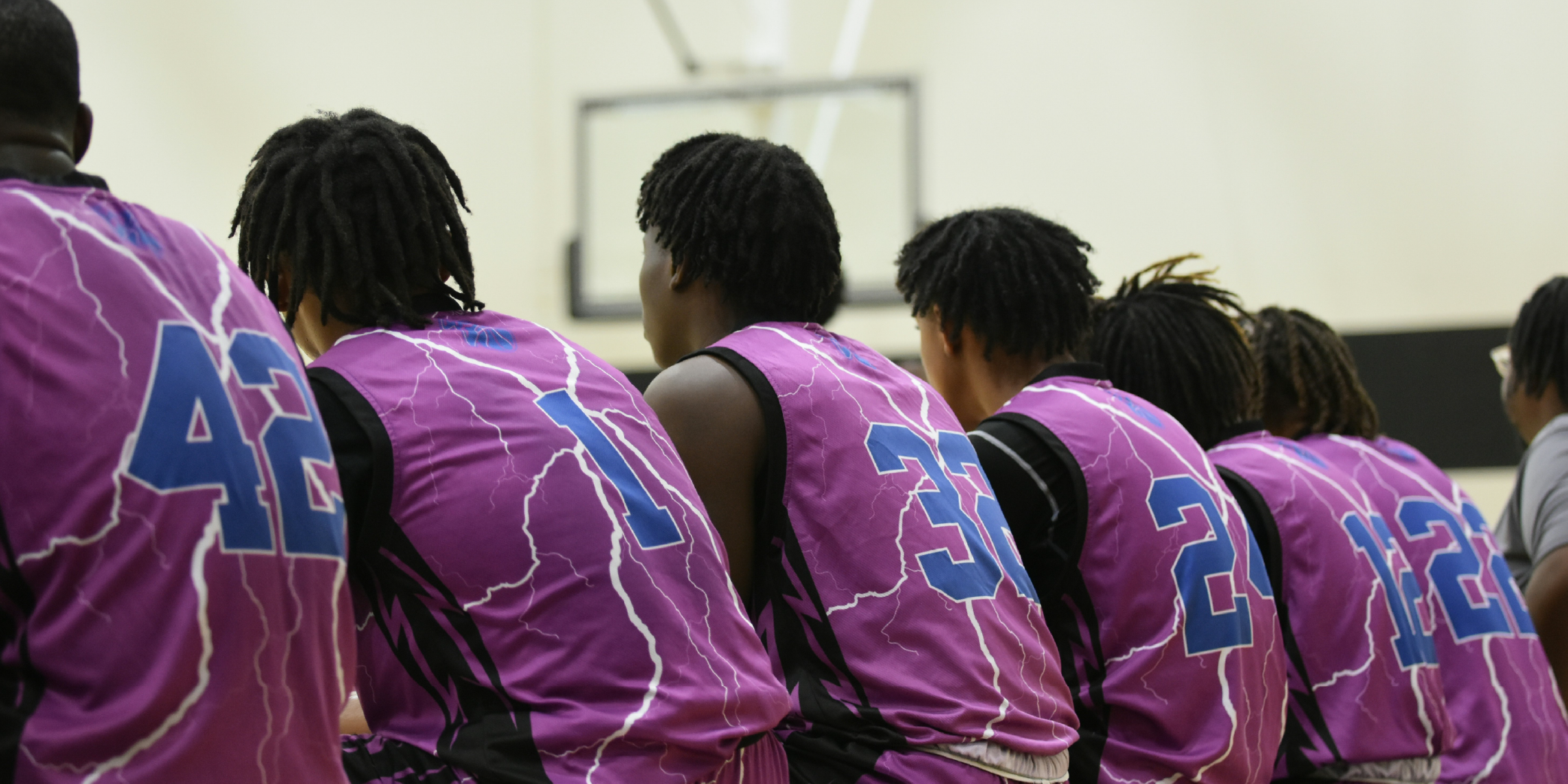 Jeunes joueurs de basketball de l'équipe U20 assis sur le banc regardant un match