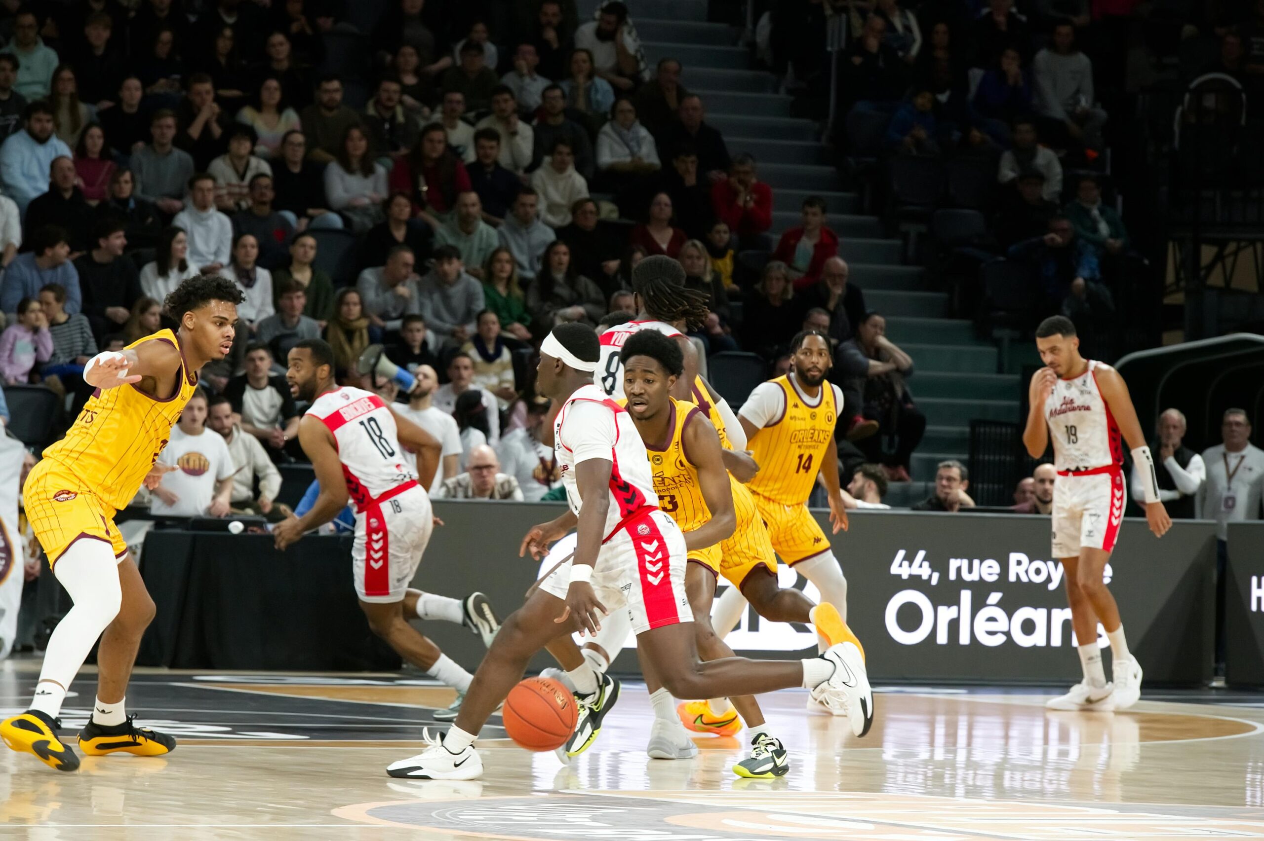 Joueur de basketball réalisant un dribble face à la défense adverse